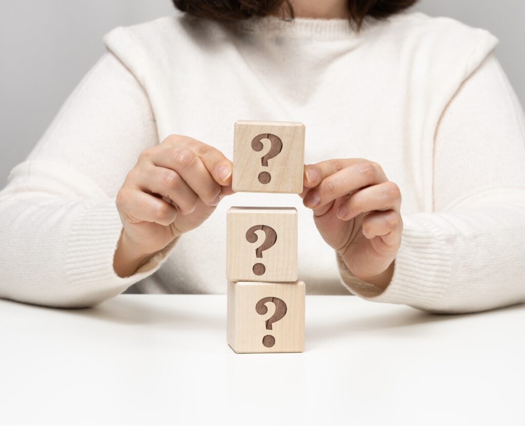 main féminine tenant un cube en bois avec un point d'interrogation, concept de réponses et de questions