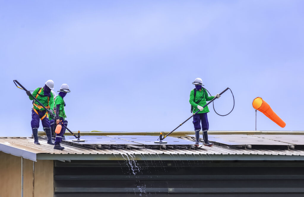 Un groupe de travailleurs professionnels du nettoyage nettoie les panneaux solaires sur le toit des bâtiments industriels