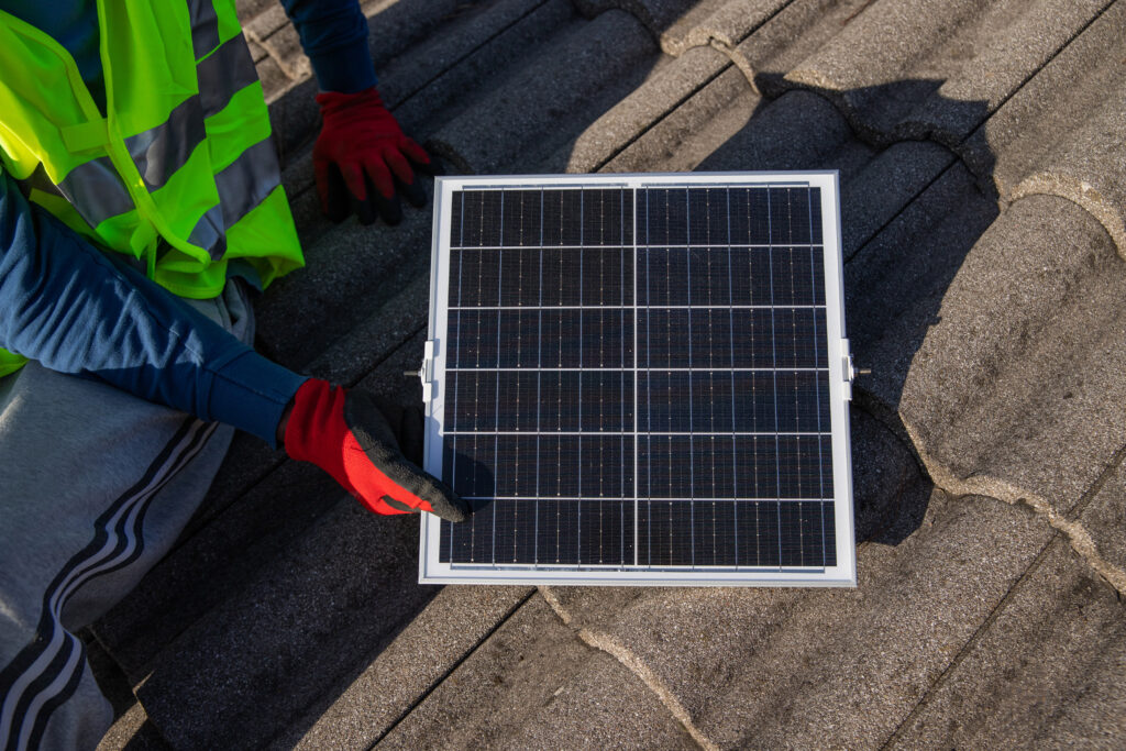 Un technicien installe un panneau solaire photovoltaïque sur un toit, énergie durable et rénovation énergétique