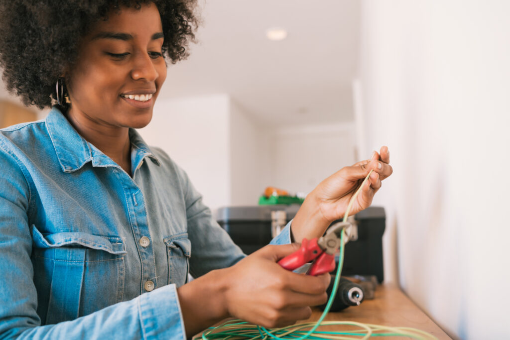 Afro femme réparant problème d'électricité à la maison.