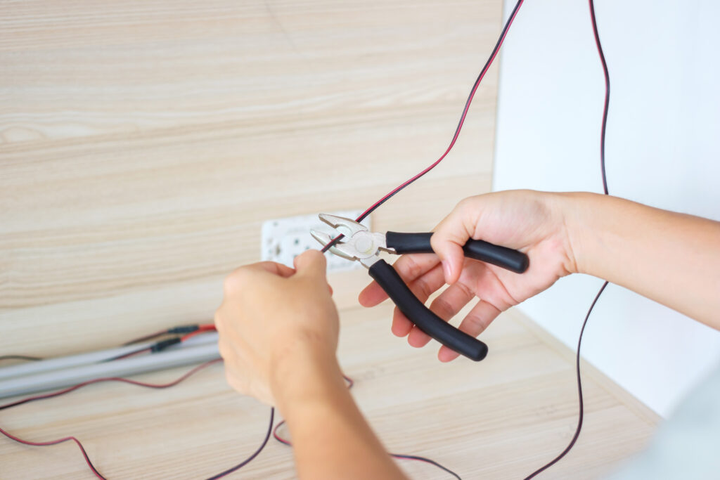 Un électricien coupe les fils électriques avec une pince pour une rénovation énergétique